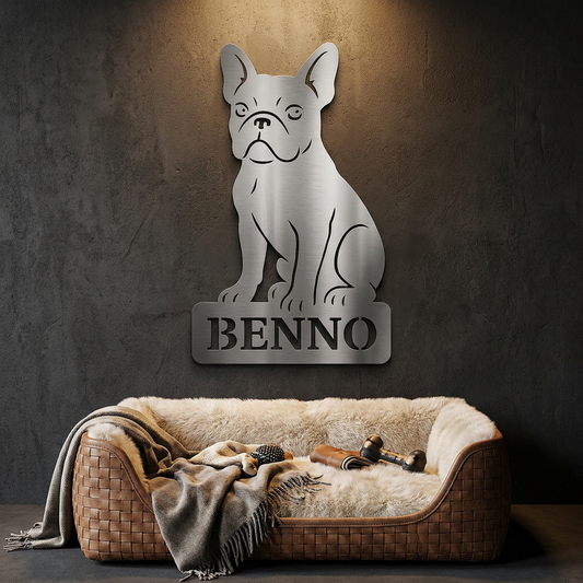 Ein Edelstahlschild mit einer Französischen Bulldogge, der Name Benno, individuell personalisierbar, vor einem Hundekorb an einer anthrazitfarbenen Wand