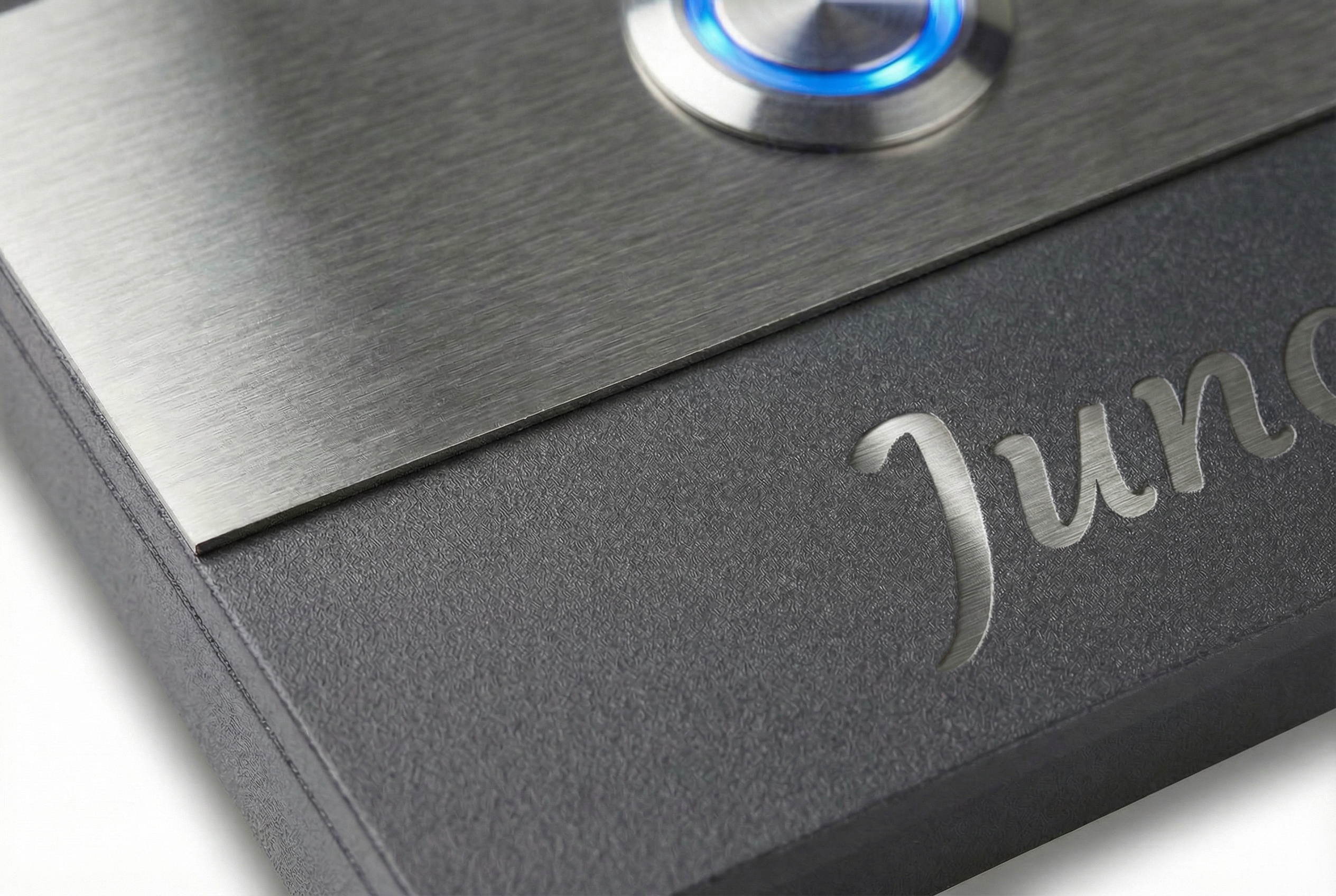 Detailaufnahme der Aufputztürklingel „Bremen“ in Anthrazit mit gebürsteter Edelstahlplatte, blauer LED am Klingeltaster und Gravur.