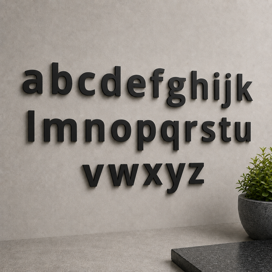 Schwarze Edelstahl-Kleinbuchstaben a bis z in Open Sans pulverbeschichtet an heller Wand