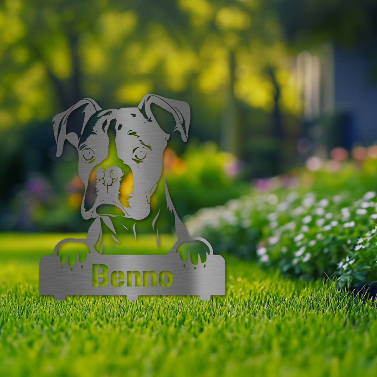 Gartenstecker mit Boxer-Hund Benno aus V2A Edelstahl, auf Wiese mit Blumen im Hintergrund platziert
