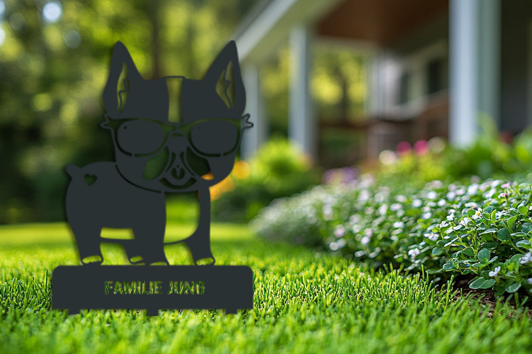 Schwarzer Gartenstecker aus Edelstahl in Bulldoggenform mit Sonnenbrille und dem Schriftzug „Familie Jung“ – dekorativ im Vorgarten vor einem Einfamilienhaus platziert.
