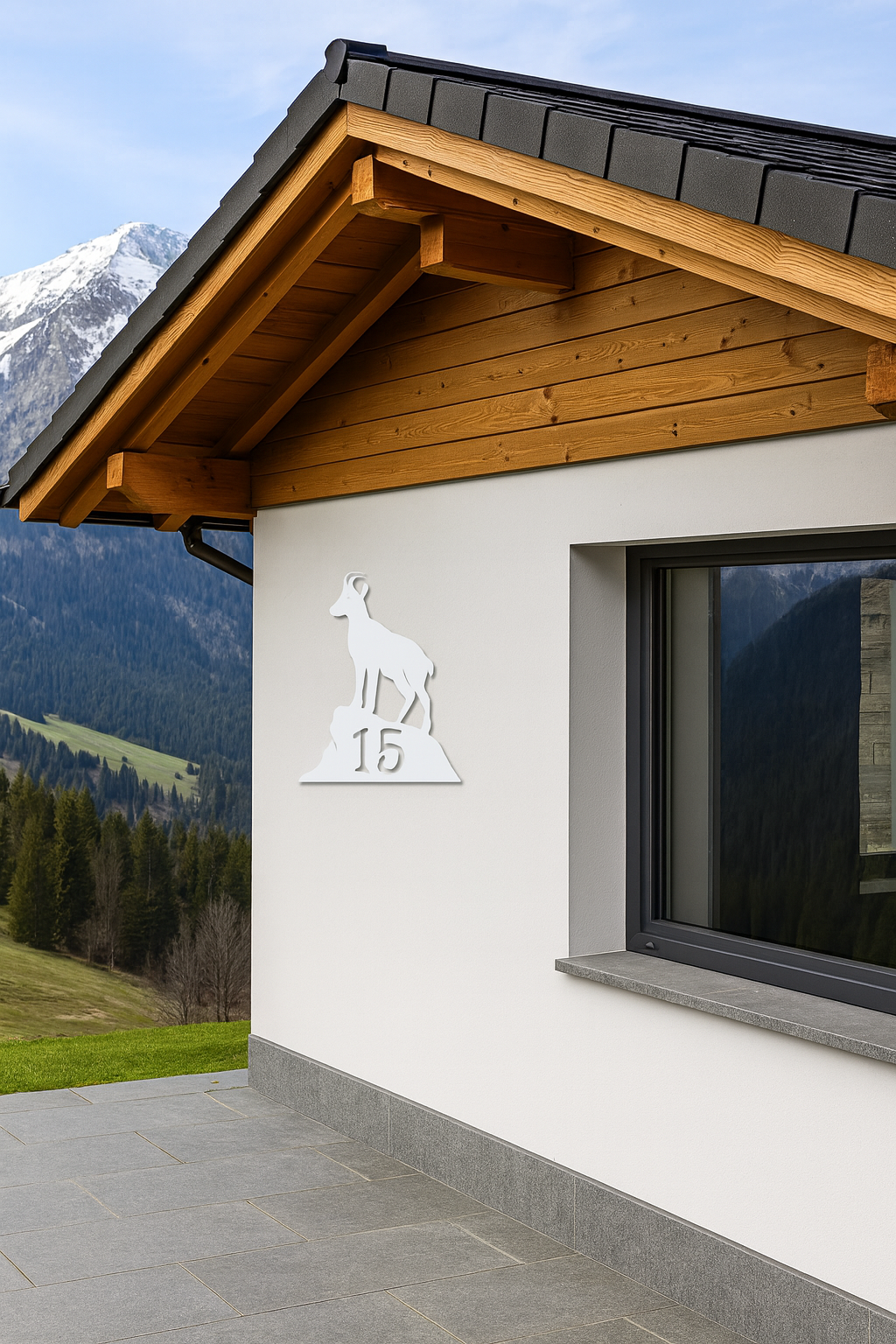 Weiße Hausnummer mit Steinbock-Motiv an modernem Haus in den Bergen