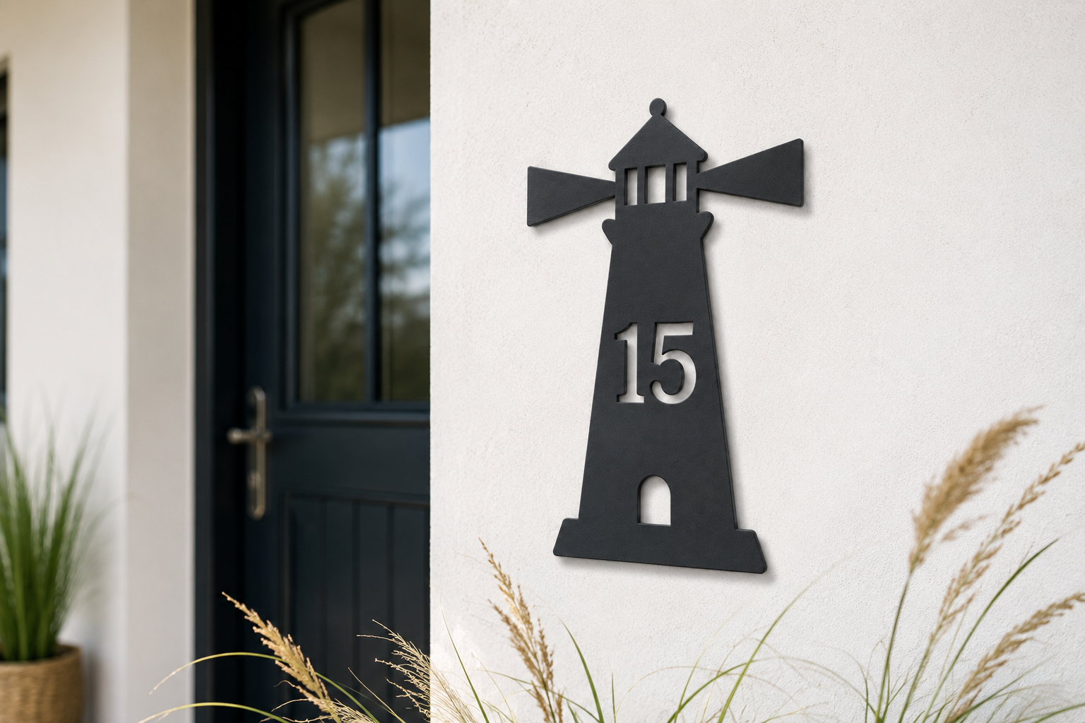 Anthrazitfarbene personalisierte Leuchtturm-Hausnummer 15 an einer hellen Außenwand neben einer dunklen Haustür